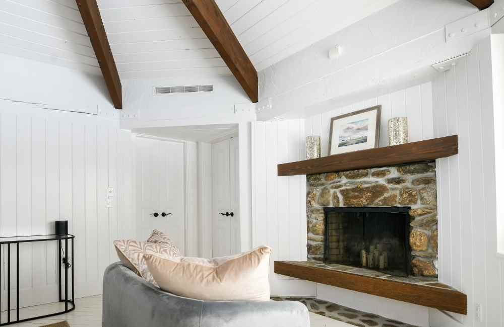 White bedroom walls with a fireplace and couch with pillows and wall decor above the mantle.