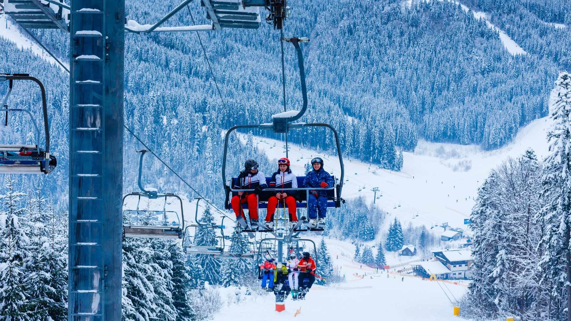 Chairlift with three people on a snowy mountain